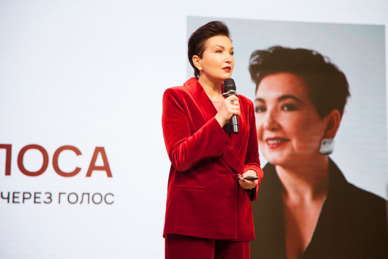 Елена Крутоверцева выступает на сцене в красном костюме