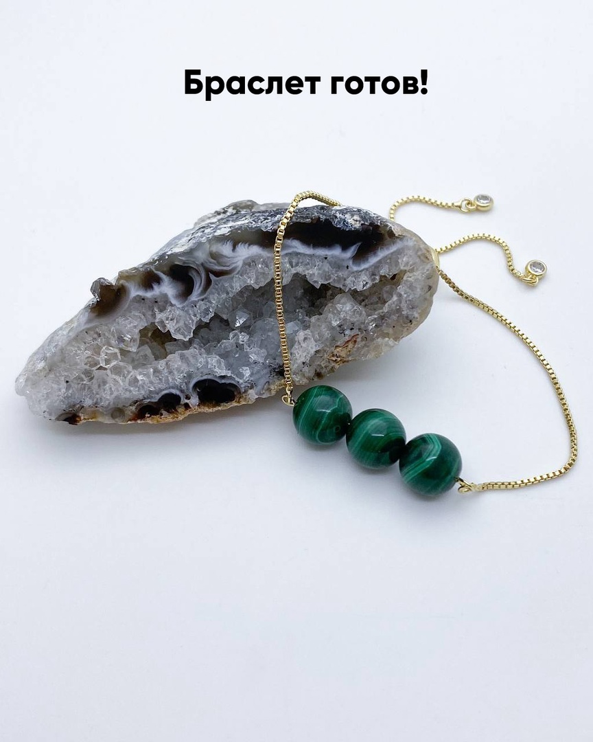 Золотистый браслет с тремя зелеными бусинами, расположенный на фоне среза агата. Надпись 'Браслет готов!' размещена в верхней части изображения.