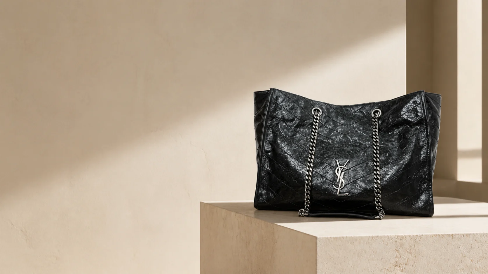 Чёрная сумка Saint Laurent на светлом каменном постаменте