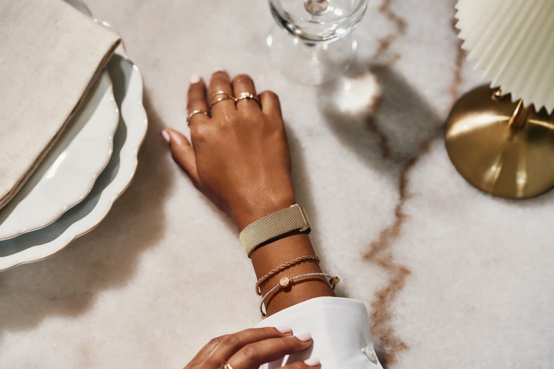 Fitbit Air с золотым Metal Mesh на запястье рядом с украшениями — официальное фото Google