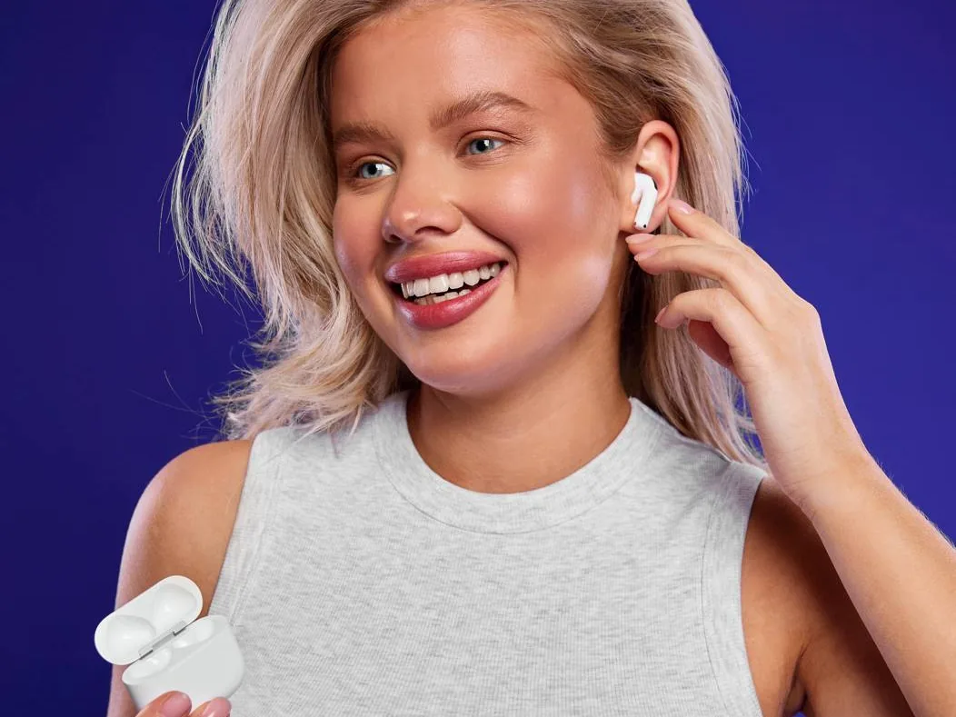 AirPods в ухе и зарядный кейс в руке