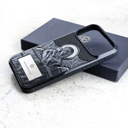 Чехол iPhone 18 Pro Max Euphoria HM Пресвятая Богородица LUX с белой персонализированной вставкой лежит рядом с тёмно-синей подарочной коробкой — рельефный лик Богородицы с младенцем обсидиан серебряный нимб кожа крокодила скат православный орнамент светлый мрамор