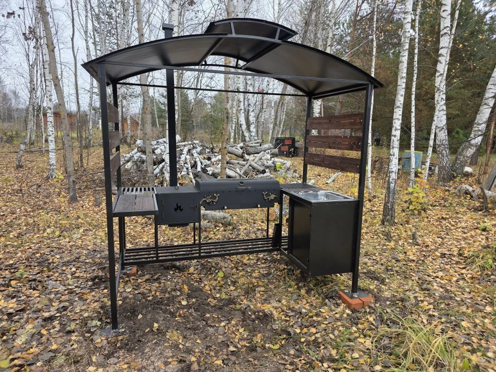 Мангальная зона из стали 5 мм с мойкой (Казань) Если вы хотите купить мангальную зону с мойкой в Казани, присмотритесь к нашему варианту: это мангальная зона 5 мм с крышей (полноценная уличная кухня/зона барбекю), где есть мангал 5 мм с жаровней 90×40×15 (рассчитан примерно на 11 шампуров), крышка барбекю с термодатчиком и шиберами для удобной регулировки тяги и температуры. Также зону можно использовать как коптильню — коптить рыбу, мясо и курицу.  Отдельно предусмотрена печь под казан 5 мм размером 40×40×30 с кольцами под казаны 3/4/6/8/10/12 литров, есть труба 80×80 с заслонкой, колосник и зольник. Для удобства сделаны столик для нарезки (стол металл+дерево), нержавеющая мойка 48×48, дровница и тубус для шампуров. Конструкция разборная, собирается на болтовых соединениях. Зона может быть в наличии в Казани, доступна доставка и установка, а также изготовление мангальной зоны под заказ под ваши размеры.