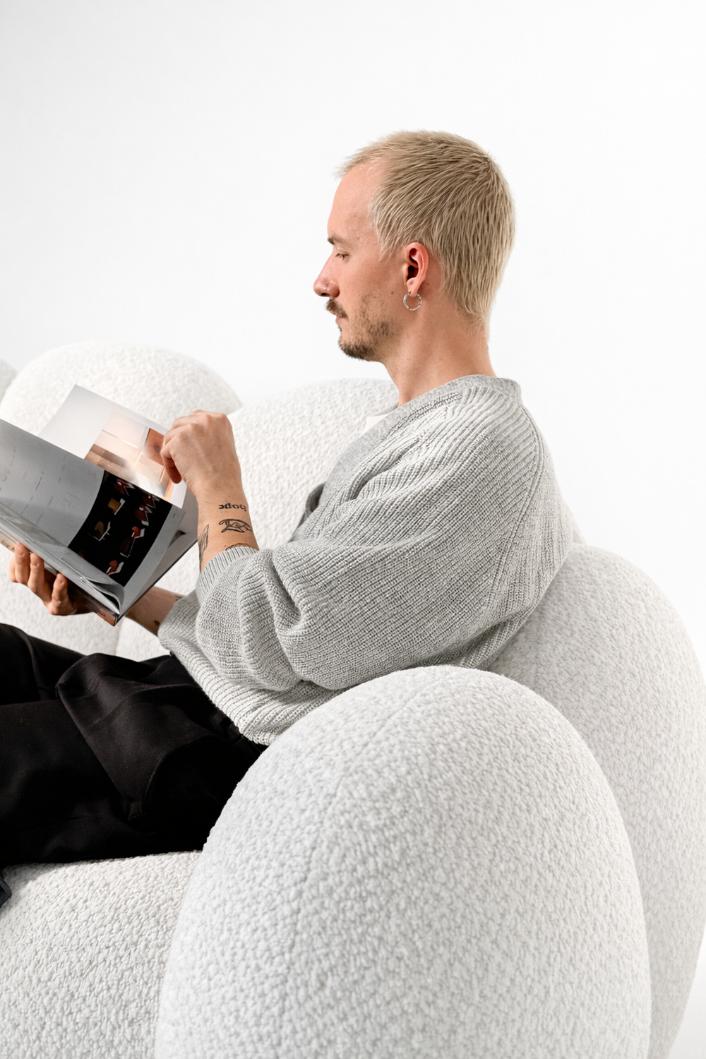 Мужчина читает книгу на белом диване Bloom, демонстрация комфортной посадки