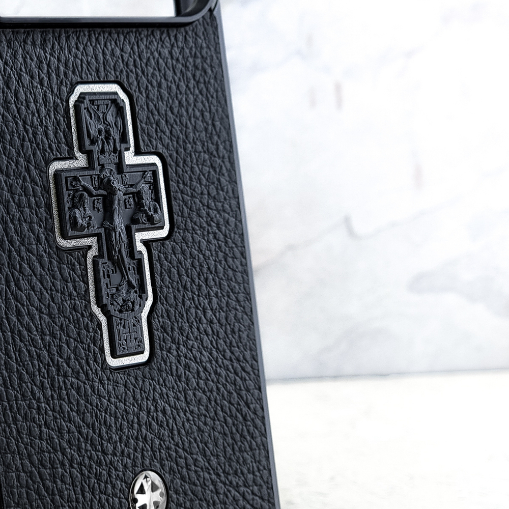 Крупный план чехла Euphoria HM Crucifix Cross для iPhone 18 Pro Max — серебряный православный крест на текстурированной чёрной коже, детали рельефа