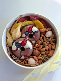 Коробка с орехами, сухофруктами и шоколадными пончиками.
