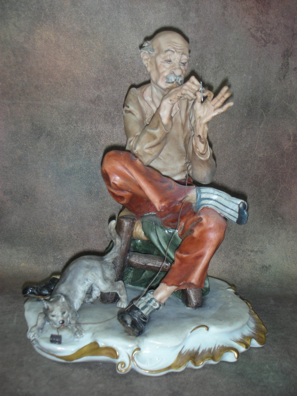 Статуэтка. Фарфор. Мужчина, зашивающий носок. Capodimonte. Италия