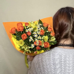 Яркий букет из кустовых оранжевых роз, желтых альстромерий и полевых ромашек в упаковке (в школу 1 сентября)