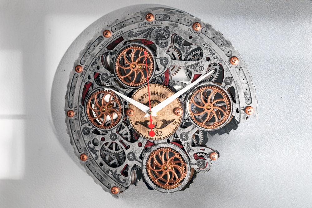 Настенные часы WOODandROOT Automaton Bite 1682 в цвете старый металл с зеркальным фоном, подчёркивающим движение четырёх шестерёнок