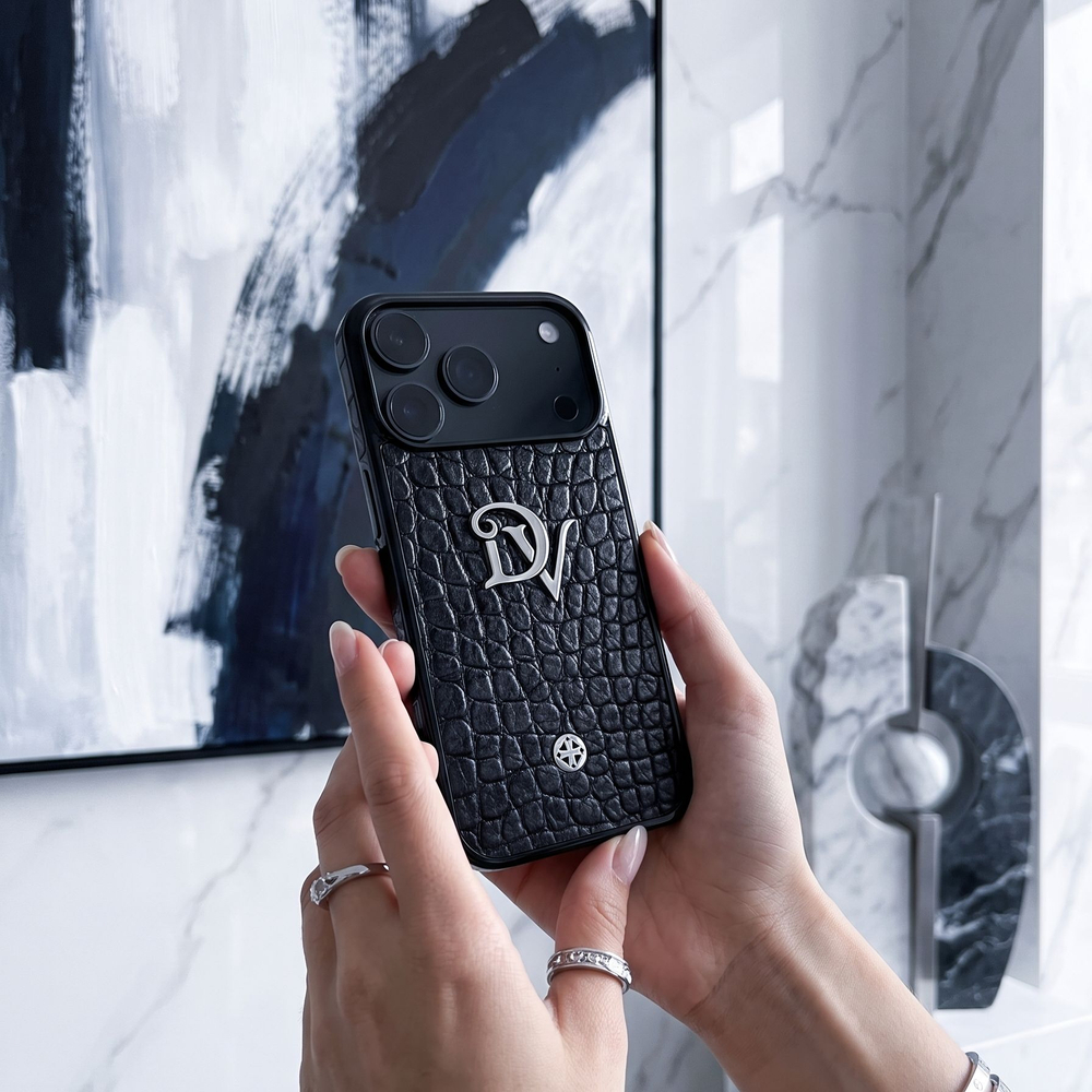 Чехол Euphoria Initials для iPhone 18 Pro с серебряными металлическими инициалами на черной коже MiniCroc - крупный план в руках с украшениями премиум интерьер